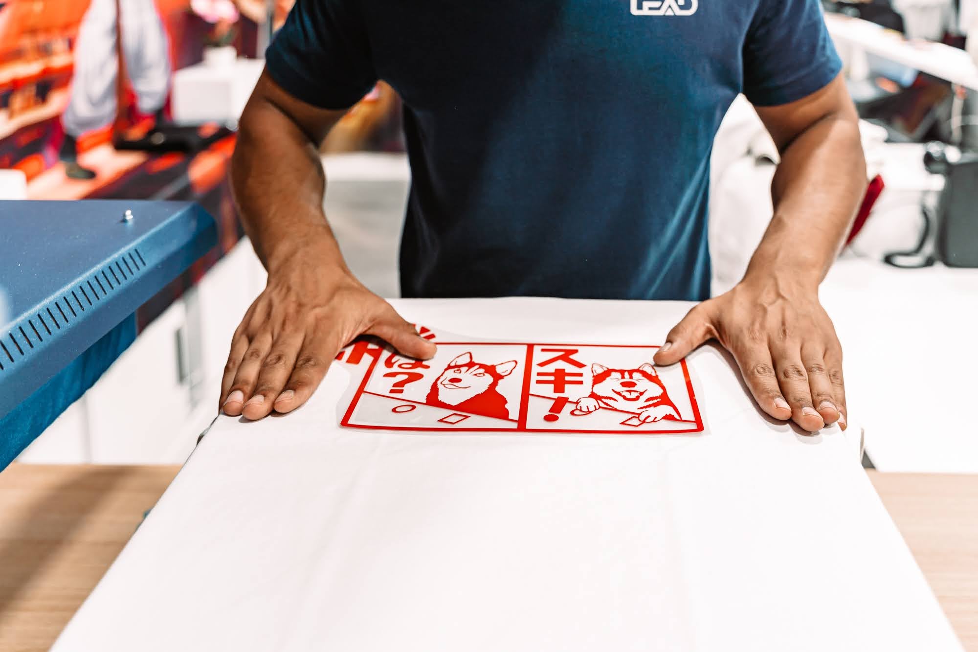 Un employé qui place un print Husky sur un t-shirt