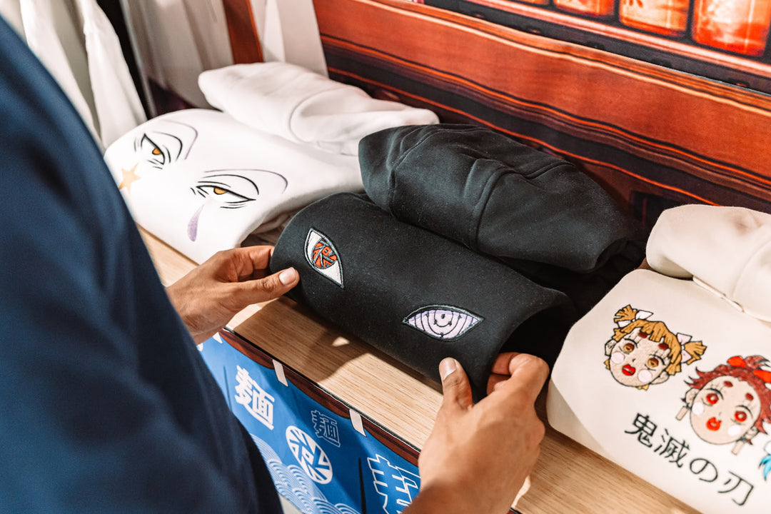 un présentoir avec des sweat à capuche hunter x hunter, naruto et demon slayer